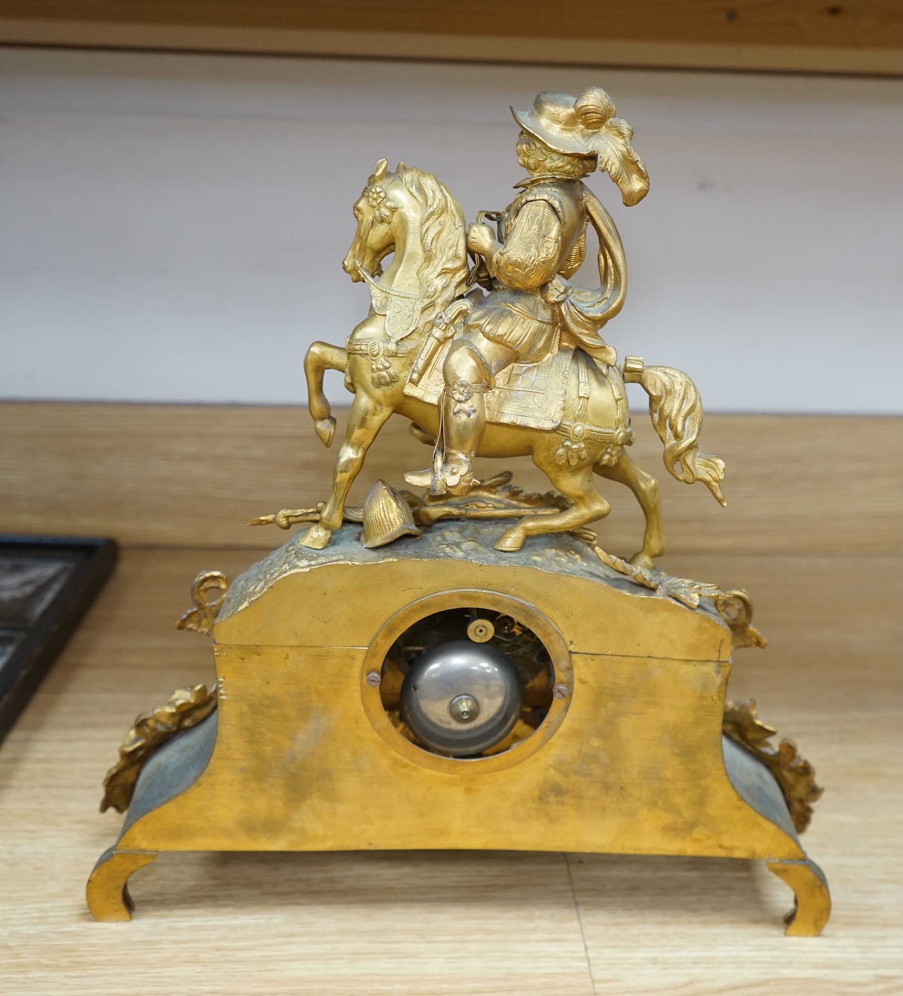 A late 19th century French ormolu mantel clock surmounted with a cavalier on horseback, key and pendulum, 38cm. Condition - fair to good